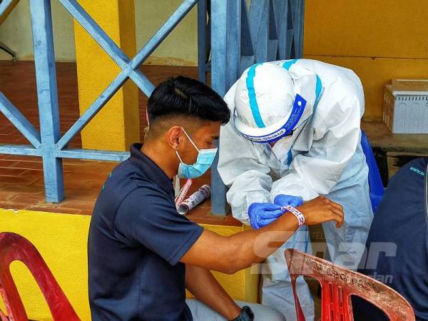 Seorang petugas kesihatan hari ini memakaikan gelang merah jambu kepada salah seorang pesakit yang diwajibkan kuarantin selama 14 hari. 