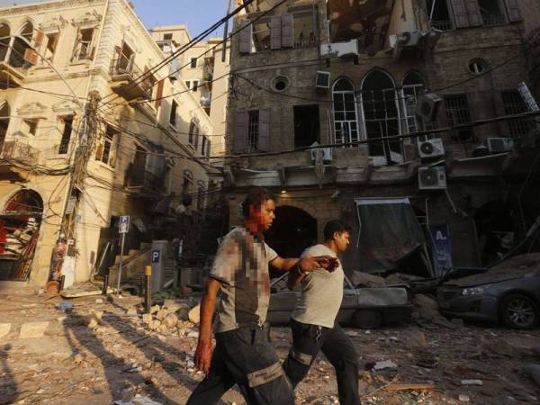 Seorang mangsa yang cedera menerima bantuan daripada orang ramai selepas letupan berkenaan. - Foto Marwan Tahtah/AFP/Getty Images
