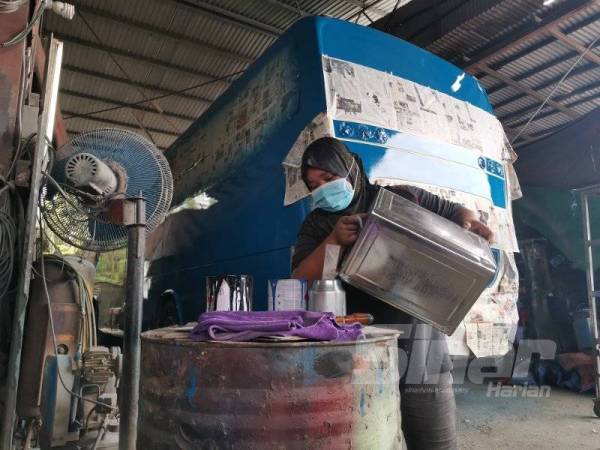 Kasni sedang membancuh cat di bengkelnya sebagai persediaan mengecat bas pelanggan.