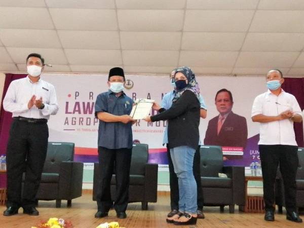 Ahmad menyampaikan sijil kepada Werdawati Mohd Zaini, 37, mewakili 40 peserta Felda yang mengikuti Kursus Forensik Perniagaan dan Pemasaran Industri Makanan di Felda Besout 4 semalam.