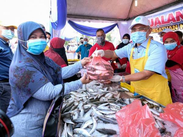 Dr Ronald Kiandee menyerahkan ikan kembung yang dilelong kepada pelanggan yang hadir pada Mini Karnival Industri Makanan Bukit Gantang 2020. - Foto Bernama