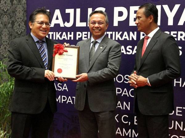 Hasni (tengah) menyerahkan lantikan Penyelaras DUN kepada Nur Jazlan (kanan) sambil diperhatikan Azmi (kiri) di Kota Iskandar hari ini.