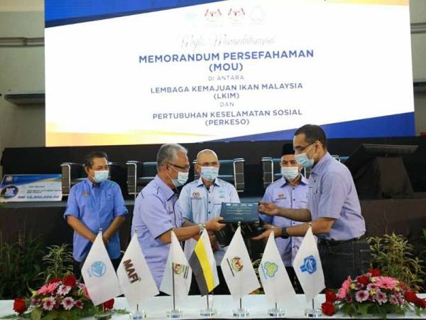 Dr Mohammed Azman (kanan) bertukar MoU yang ditandatangani dengan Othman sambil disaksikan Ronald (tengah) di Dewan Bunga Raya dekat Changkat Jering hari ini.