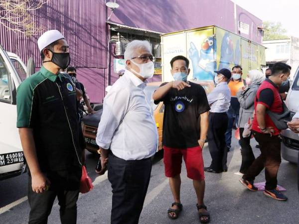 Menteri Dalam Negeri Datuk Seri Hamzah Zainudin bersama Pemilik perniagaan Hot Burger Malaysia Mohd Asri Hamid (kiri) ketika meninjau lokasi perjudian haram yang berlaku di sekitar Bandar Baru Sungai Buloh hari ini.
