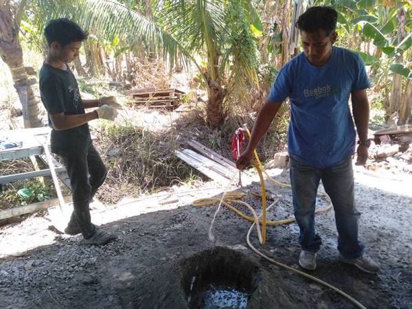 Kamarul (kanan) bersama pekerjanya membuat bancuhan simen untuk menghasilkan rak pasu bertingkat.