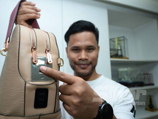 Hilman menunjukkan teknologi finger print yang terdapat pada beg tangan ciptaannya.