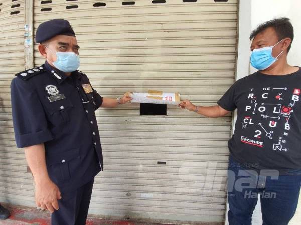 Noorzainy (kiri) menunjukkan lubang yang ditebuk pada pintu depan premis.