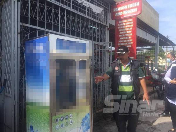 Mohd Wazir menunjukkan mesin air bertapis yang disita.