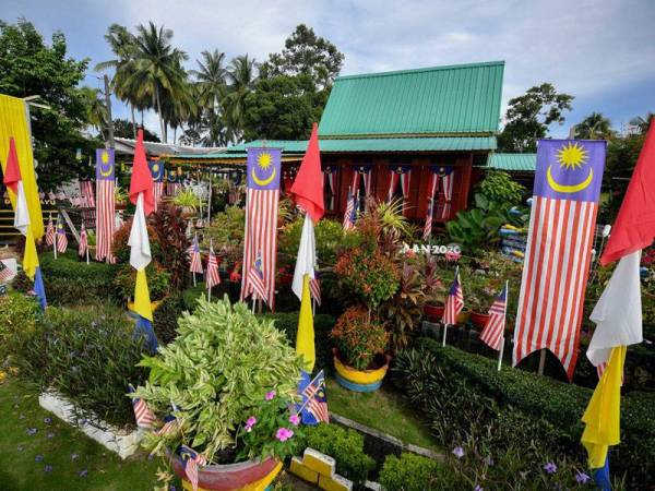 Pemilik rumah, Mohammad Muzzamman Othman, 31, menghias pekarangan rumahnya dengan Jalur Gemilang ketika ditemui foto Bernama di Felda Tun Ghafar, hari ini.