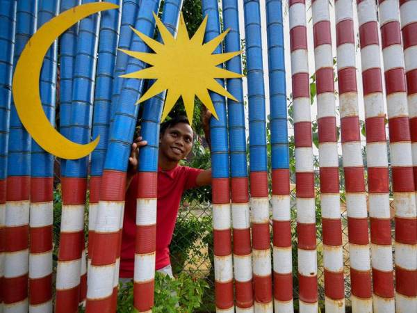 Pemilik rumah, Mohammad Muzzamman Othman, 31, menghiasi pekarangan rumahnya dengan tin-tin kosong yang diwarnakan dan disusun menjadi Jalur Gemilang ketika ditemui foto Bernama di Felda Tun Ghafar, hari ini.