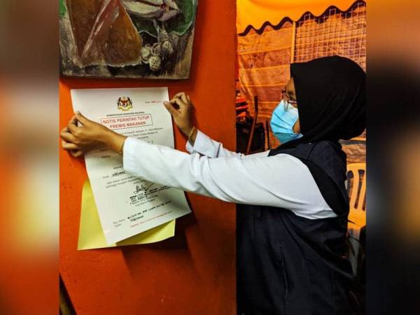 Pegawai penguat kuasa JKN Pahang menampal notis arahan tutup terhadap premis makanan yang didapati berada dalam keadaan kotor hasil pemeriksaan dalam Operasi Caras Hijau Bersepadu di Cameron Highlands kelmarin. - Foto ihsan JKN Pahang