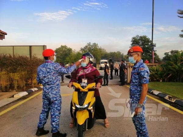 Petugas keselamatan melakukan ujian suhu ke atas petugas pada hari penamaan calon di Dewan Sri Tanjung, Majlis Daerah Tanjung Malim (MDTM) hari ini.
