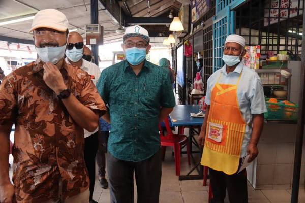 Mukhriz (kanan) bersama Amir Khusyairi ketika sesi bertemu pengundi di Medan Arked Mara, Slim River hari ini.