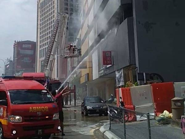 Anggota bomba sedang memadamkan kebakaran sebuah stor di sebuah hotel di Jalan Maharajalela di sini pagi tadi.