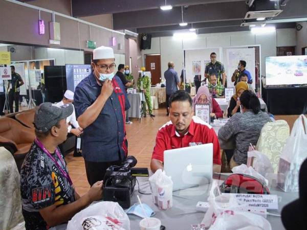 Mohd Akmal (berdiri) menyantuni petugas media ketika melawat Pusat Media KKMM PRK DUN Slim di Tanjung Malim hari ini.