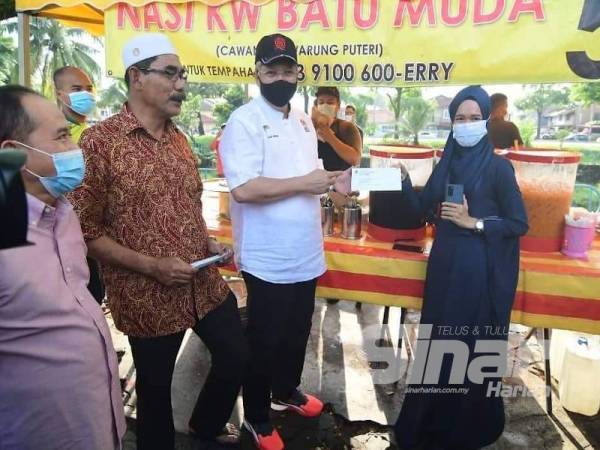 Annuar (dua dari kanan) menyampaikan lesen penjaja kepada salah seorang peniaga di Batu Muda hari ini.