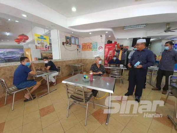 Rozali melihat salah satu meja yang telah diikat dengan dua kerusi di Restoran Nasi Kandar Pelita untuk memastikan penjarakan fizikal dalam kalangan pelanggan diamalkan.