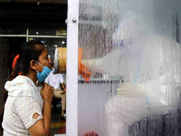 Seorang pekerja kesihatan mengumpulkan sampel ujian Covid-19 daripada seorang wanita di pusat pemeriksaan bergerak di New Delhi, India. Foto: Xinhua