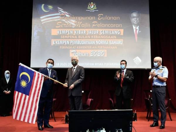 Ismail Sabri (tiga dari kanan) menyerahkan Jalur Gemilang kepada Ketua Setiausaha Kementerian Pertahanan, Datuk Seri Muez Abdul Aziz (dua dari kiri) pada Perhimpunan Bulanan dan Majlis Pelancaran Kempen Kibar Jalur Gemilang sempena Bulan Kebangsaan dan Kempen Pembudayaan Norma Baharu Peringkat Kementerian Pertahanan 2020 di Wisma Pertahanan, Kuala Lumpur hari ini. - Foto Bernama
