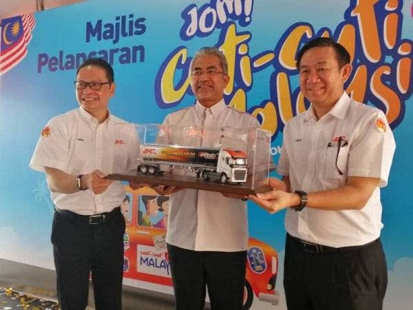 Leslie (kanan) menyampaikan cenderahati kepada Musa (tengah) pada pelancaran peraduan Jom! Cuti-cuti Malaysia di Kuala Lumpur.