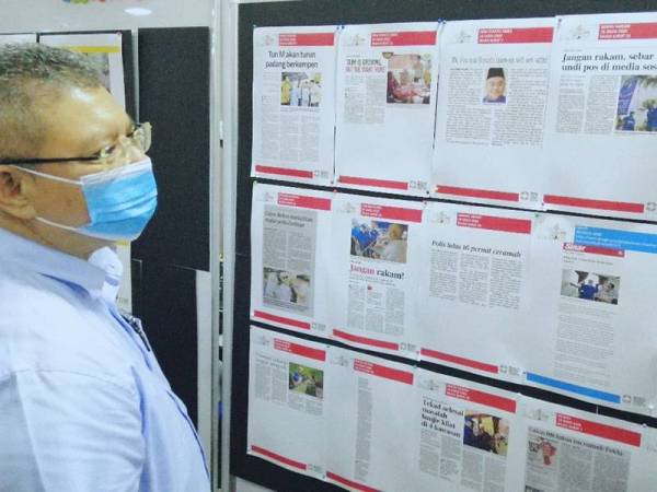 Saifuddin melihat keratan akhbar yang dipaparkan di papan maklumat Pusat Media Pilihan Raya Kecil (PRK) Slim sempena Majlis Ramah Mesra bersama Media hari ini.