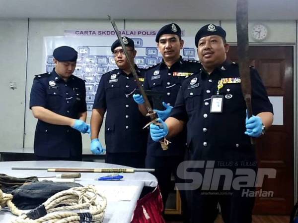 Azhar (kanan) menunjukkan parang yang ditemui dalam kenderaan dinaiki suspek pada sidang media di Ibu Pejabat Polis Daerah Kulim hari ini.