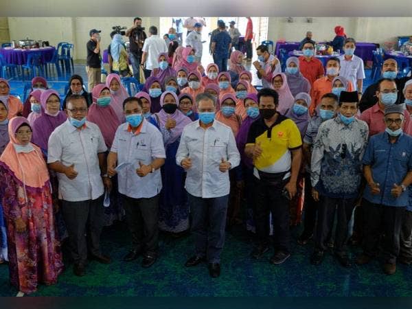 Mustapa (tengah) bergambar bersama warga peneroka ketika hadir sempena PRK DUN Slim di Felda Trolak Utara hari ini. Foto: Bernama