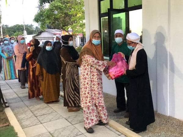 Agihan bantuan disampaikan oleh Rosli (kanan) dan Rohiman di luar Baitul Rizk yang menjadi rumah menempatkan barangan keperluan makanan asasi khas kepada golongan yang memerlukan bantuan.