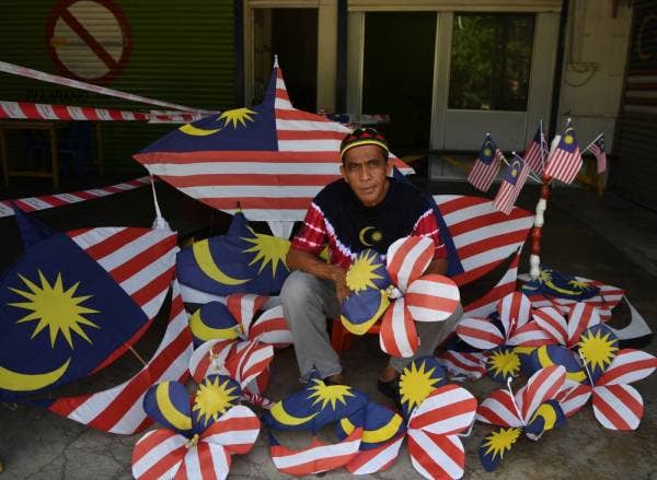 
Wan Rahimi memperbetulkan replika bunga raya dan wau bulan yang diperbuat daripada Jalur Gemilang sebelum menghiasi kedainya semalam.
