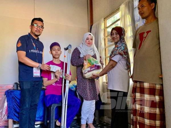 Keluarga Muhammad Mikael menerima sumbangan daripada Che Norhayati (tengah) ketika menziarahi keluarga tersebut di Kampung Pantai Mek Mas semalam.