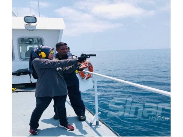 Wartawan Sinar Harian, Adila Sharinni Wahid mencuba senjata jenis Pistol CZ sambil diperhatikan oleh Muhd Nur Syam Asmawie dalam program yang turut diadakan bagi menghargai pengamal media di Kelantan.