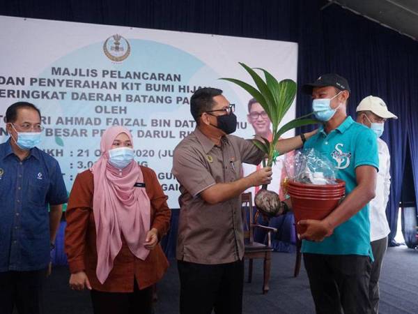 Ahmad Faizal menyerahkan Kit Bumi Hijau kepada seorang penerima di Chenderiang hari ini.