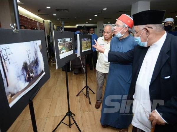 Zulkifli melihat gambar ketika melawat pameran sambil diiringi Presiden Mapim, Mohd Azmi Abdul Hamid dan Timbalan Pengerusi Kumpulan Karangkraf, Datuk Muhammad Nasir Hamzah selepas perasmian Muafakat NGO Islam Tangani Nasib Ummah di Karangkraf hari ini. Foto Sinar Harian/Rosli Talib
