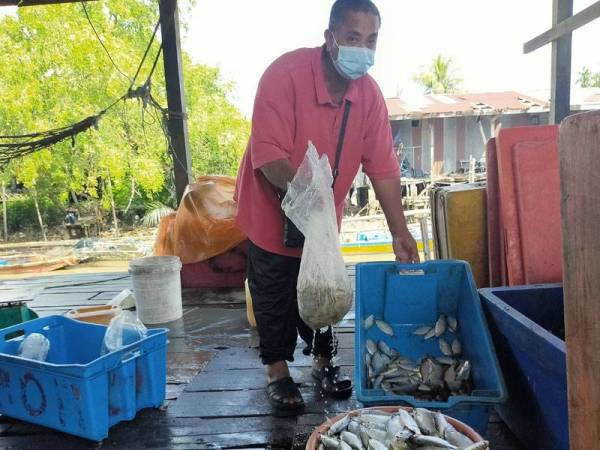 Abd Razak menunjukkan hasil tangkapan yang tidak terjual di pelantar ikan di sini hari ini.