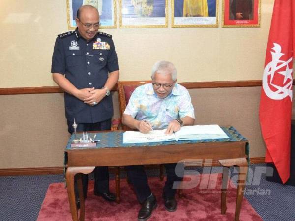 Hussamuddin turut menandatangani buku pelawat sebaik tiba di Pejabat Ketua Polis Kelantan sambil diperhatikan Shafien.