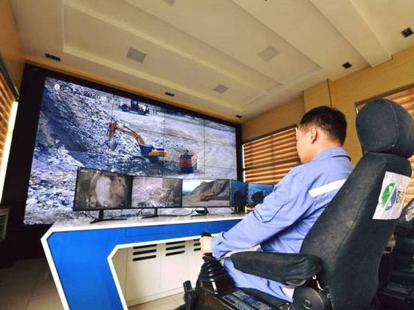 Pekerja syarikat China Molybdenum mengawal jentera menggunakan alat kawalan jauh 5G. - Foto: Agensi