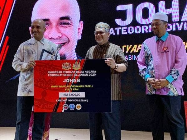 Mohd Amar (tengah) menyampaikan Anugerah Perdana Belia Negara Peringkat Negeri Kelantan kepada Mohd Syafiq Mohamad Fadeli di Hotel Perdana hari ini.