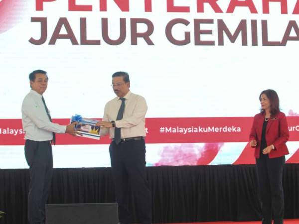 Mohd Zuki (dua dari kanan) menyerahkan bendera kepada Mohd Khairul Adib sebagai simbolik perasmian Program KSN@Merdeka Bersama Penjawat Awam sempena Sambutan Bulan Kebangsaan dan Kibar Jalur Gemilang di Dataran Putra hari kelmarin. - FOTO ASRIL ASWANDI SHUKOR