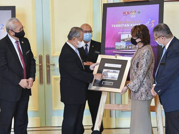 Perdana Menteri Tan Sri Muhyiddin Yassin melihat dari dekat Setem Keluaran Khas Jubli Perak Putrajaya semasa majlis pelancaran setem itu dan Duit Syiling Peringatan Jubli Perak Putrajaya di bangunan Perdana Putra hari ini.