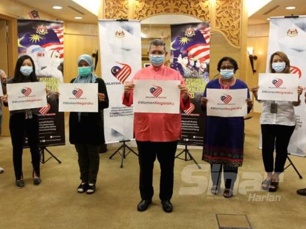 Saifuddin (tengah) memegang plakad #Momen Negaraku selepas temu bual khas sempena Bulan Kebangsaan 2020 bersama Menteri Komunikasi dan Multimedia di Putrajaya hari ini. - FOTO ASRIL ASWANDI SHUKOR