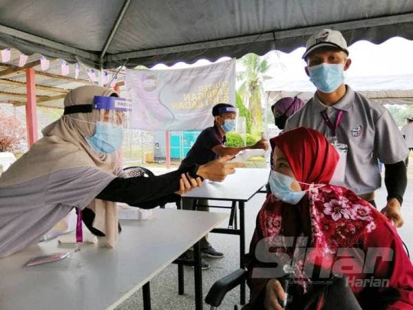 Zamzarina Md Sharif, 35, dibantu petugas Suruhanjaya Pilihan Raya (SPR) menjalani pemeriksaan suhu sebelum dibawa ke tempat pengundian di Pusat Mengundi Sekolah Kebangsaan (SK) Besout 5, hari ini.