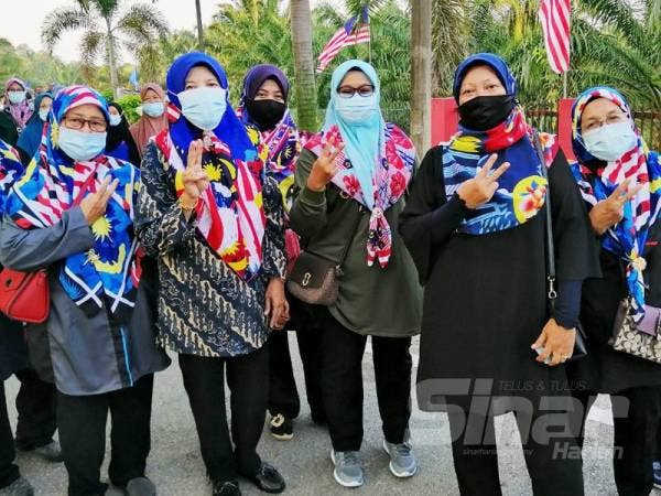 Norhidayah Mohd Zawawi, 35, (tengah) bersama rakan-rakan Gerakan Persatuan Wanita Besout 5 tampil sedondon mengenakan tudung corak Jalur Gemilang sempena semangat bulan kemerdekaan pada hari pengundian di Pusat Mengundi Sekolah Kebangsaan (SK) Besout 5, hari ini.