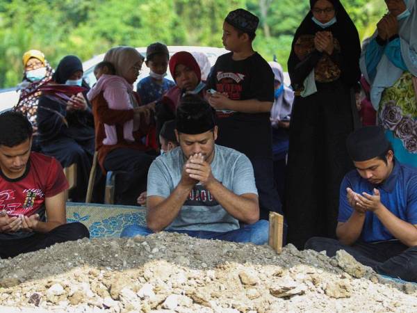 Mohd Bukhari (tengah) membaca doa untuk jenazah anaknya yang dikebumikan di Tanah Perkuburan Islam Senawang.