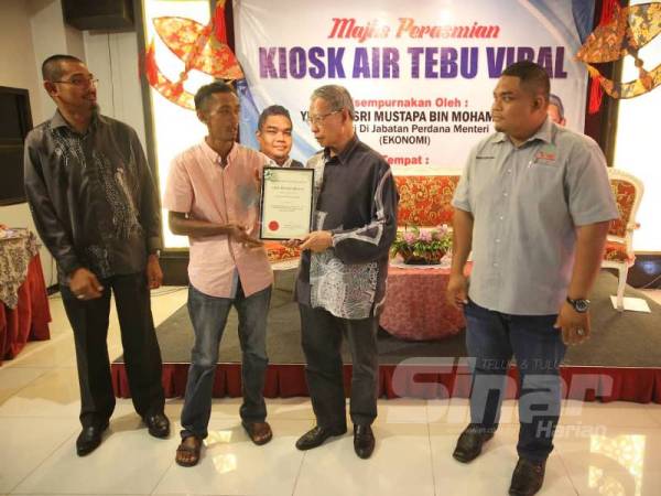 Mustapa (dua dari kanan) menyampaikan sijil penghargaan kepada Raja Sayuti Raja Ismail yang berjaya mencatatkan pengeluaran tebu tertinggi sempena perasmian Kiosk Air Tebu Viral di Royal Guest House hari ini.