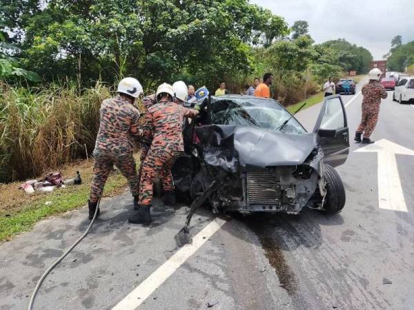 Anggota bomba mengeluarkan seorang mangsa yang tersepit di tempat duduk pemandu.