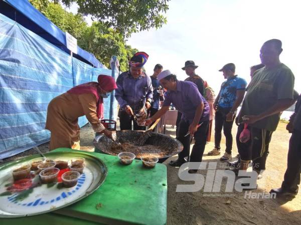 Ariffin (dua dari kiri) mencedok wajik atau pulut manis yang sinonim dengan masyarakat tradisional Melayu yang turut disajikan sempena program Semarak Merdeka 63 yang diadakan di Kalang Warisan, Kampung Pulau Manis, Serada semalam.