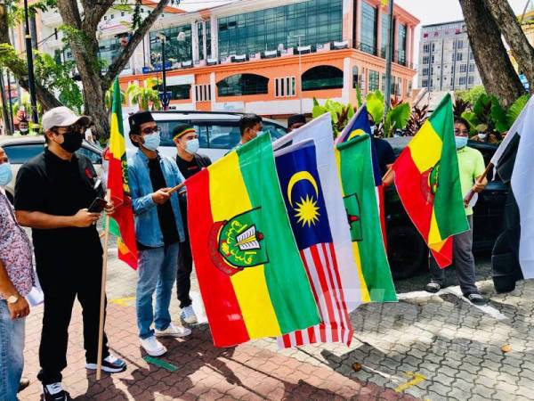 Peserta himpunan aman mengibarkan Jalur Gemilang dan bendera Pahang di pekarangan Taman Kerang, Kuantan hari ini. 
