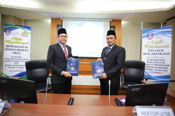 Ismail (kanan) dan Zainor menunjukkan dokumen MoU yang dimeterai antara UiTM dan MPPG untuk memperkukuh kerjasama dalam pelbagai bidang di Menara Aqabah, Pasir Gudang hari ini.