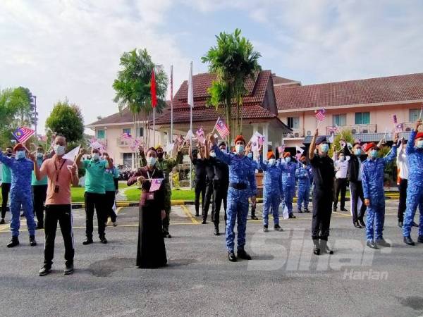 Awang Askandar (depan, tiga dari kiri) mengibarkan Jalur Gemilang sempena sambutan Hari Kebangsaan ke-63 di Hotel Seri Malaysia hari ini. 