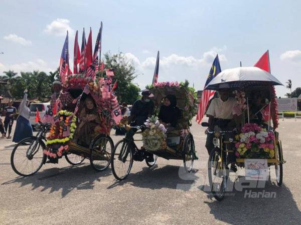 Raja Rusmin menaiki beca berhias Jalur Gemilang mengelilingi kawasan berhadapan Padang Merdeka sambil melihat monumen sejarah di lokasi itu.